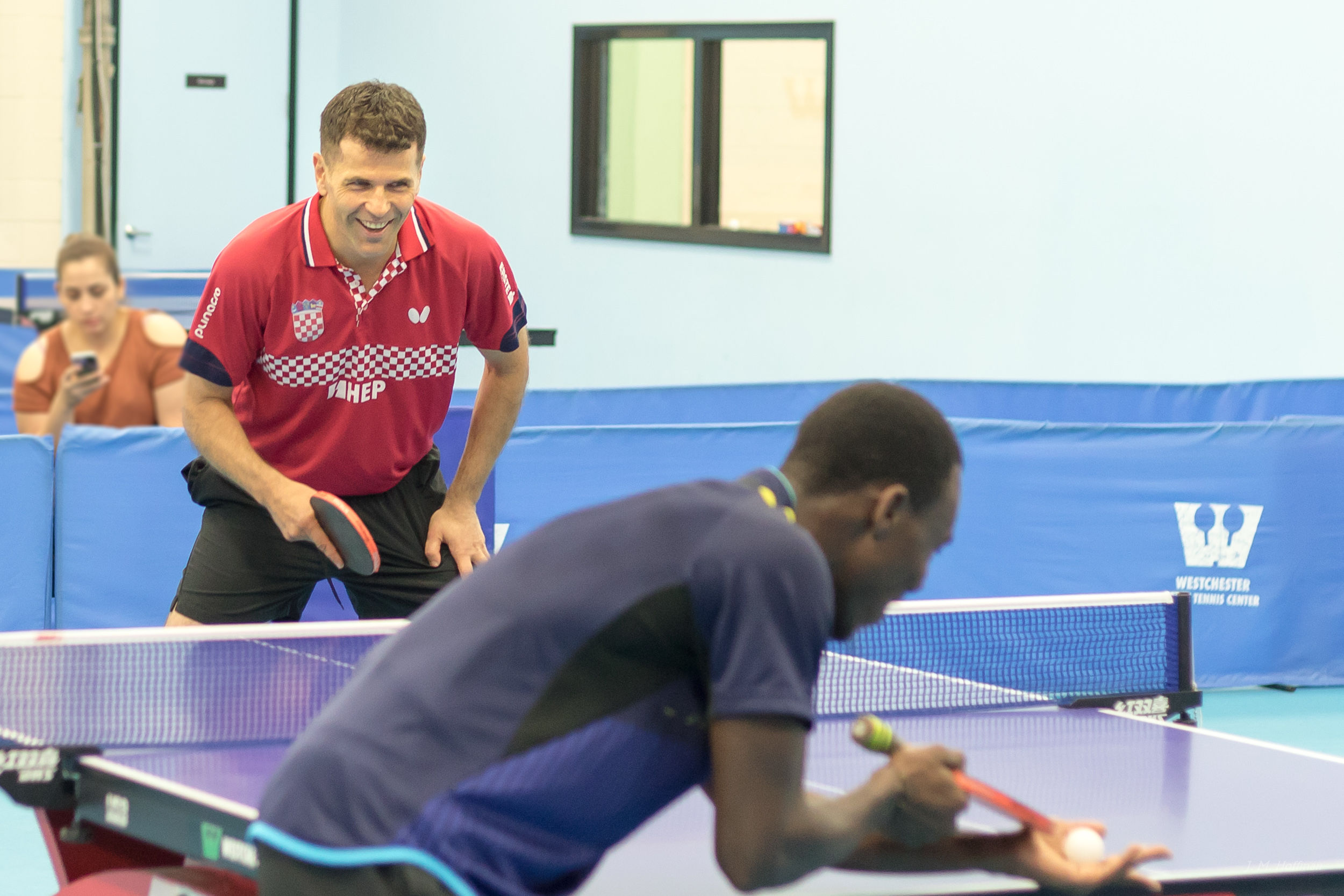 Kokou serves to Zoran in an exhibition game.: 